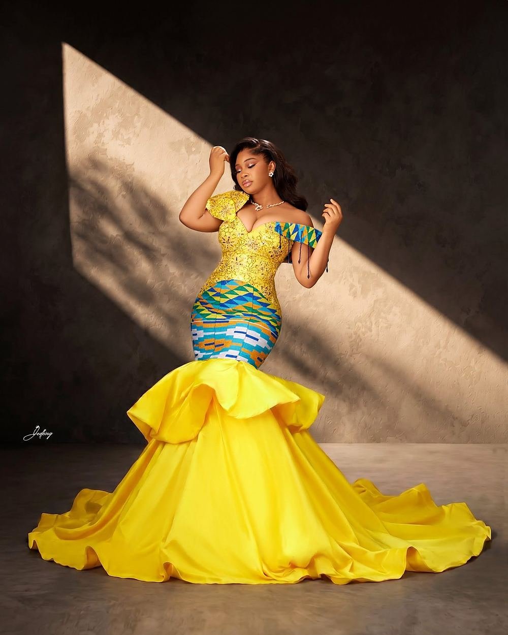 Kente Sovereign, a yellow mermaid gown with kente bodice in dramatic sunlight