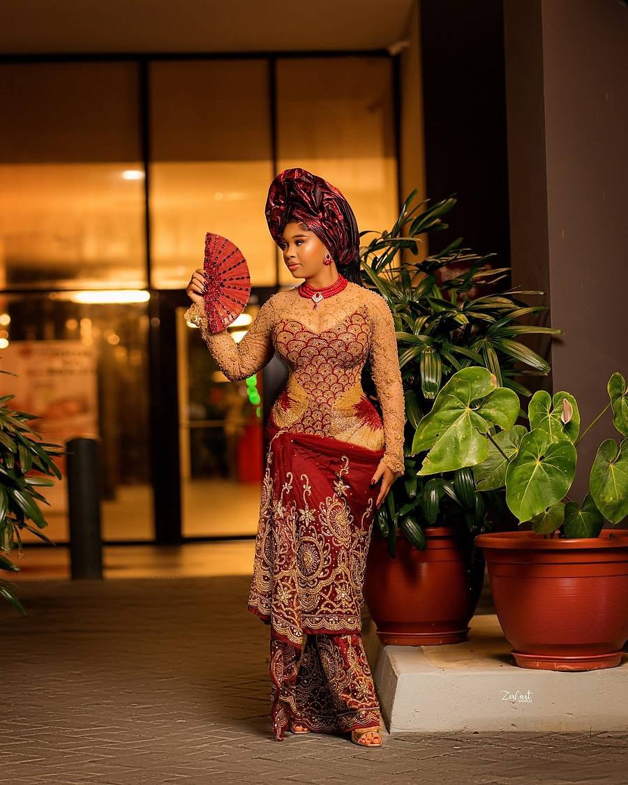 Sovereign Red, coral-toned traditional ceremonial ensemble with hand fan