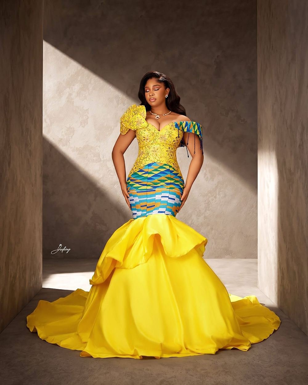 Kente Mermaid, sculpted yellow kente gown in a sunlit doorway